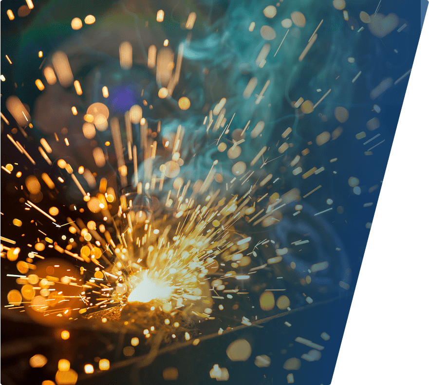 Bright orange and yellow sparks flying outward from a welding or grinding process, with some blue smoke swirling in the background. The image has a dynamic and energetic feel with a dark background that highlights the glowing sparks.