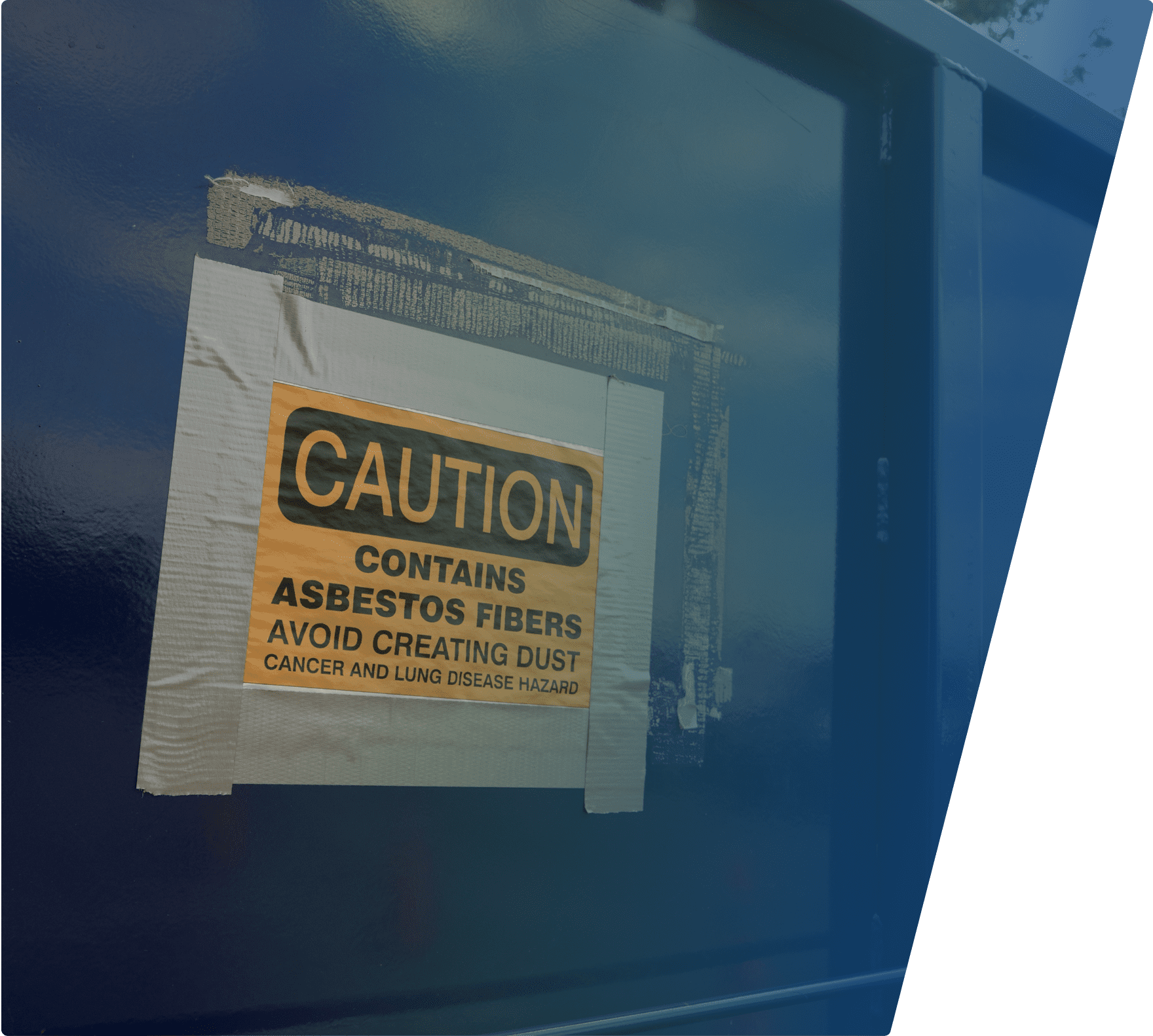 Caution sign taped to a blue metal surface, warning about asbestos fibers and advising to avoid creating dust due to cancer and lung disease hazards.