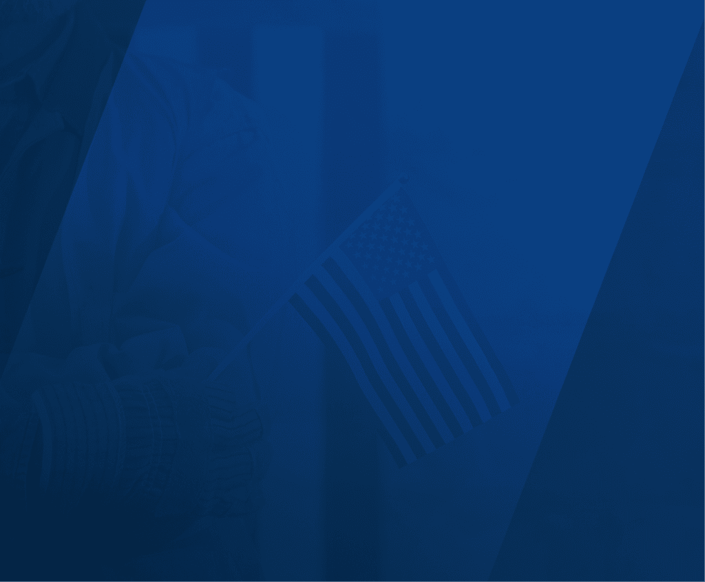 A person wearing work gloves and a jacket is holding a small American flag on a stick. The image has a greenish-blue overlay with diagonal transparent stripes.