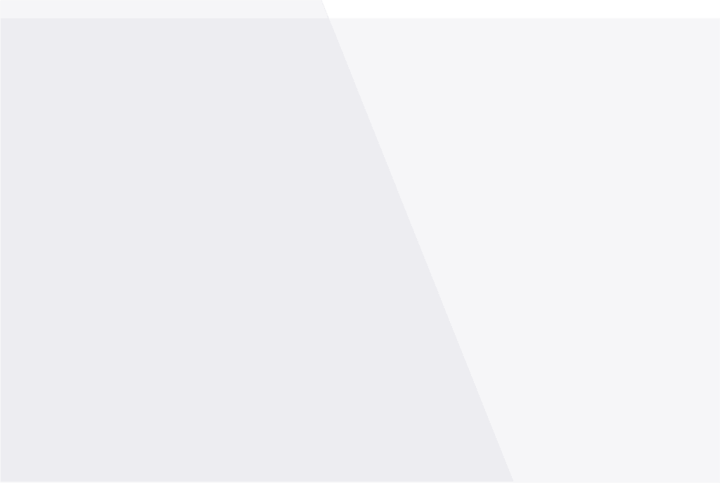 A modern, minimalist kitchen with a large island in the center featuring a built-in sink and a wooden countertop extension for seating. The kitchen has sleek white cabinetry, a built-in oven, and a stainless steel refrigerator. There are three pendant lights hanging above the island, and the space is illuminated by natural light from large windows. The floor is light wood, and the overall color scheme is neutral with white, wood, and stainless steel accents.
