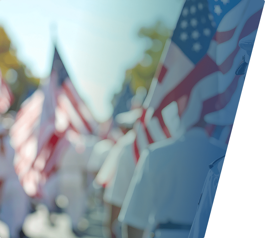 A group of people dressed in white uniforms, likely military personnel, holding American flags. The image is taken outdoors with a bright sky and some trees in the background, but the focus is soft and the details are blurred.